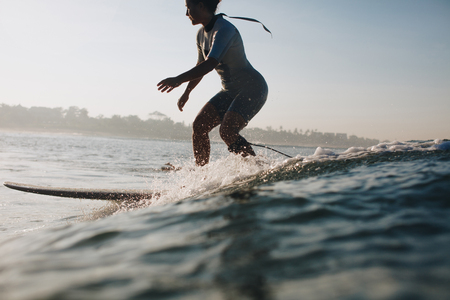 silhouette of sportswoman surfing in ocean, coastline on backgroundの写真素材