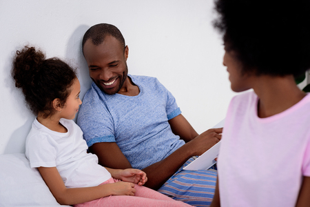 Smiling African american parents and daughter looking at each other at homeの写真素材