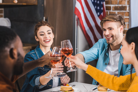 Cropped shot of happy young multiethnic friends clinking wine glasses