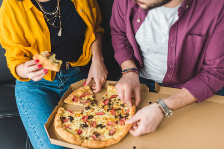Cropped view of young couple eating pizzaの写真素材