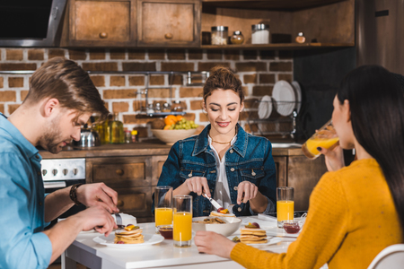 Young friends having breakfast together at homeの写真素材
