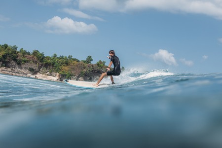 Active man surfing wave on surf board in ocean