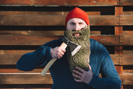 young man with beard made of wood bark and axe in hand outdoorsの写真素材