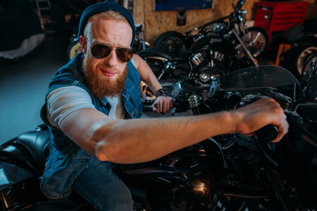 close-up portrait of handsome young man on bike at garage
