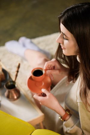 selective focus of young woman with cup of coffee at homeの写真素材