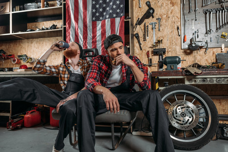 exhausted mechanics having lunch together at garage