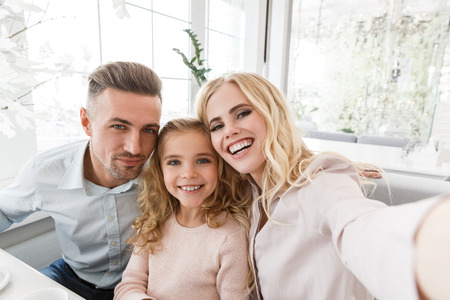 happy young family taking selfie in restaurantの写真素材
