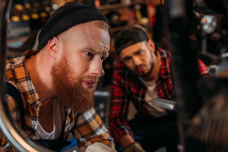 handsome mechanics looking at motorcycle to repair at garageの写真素材