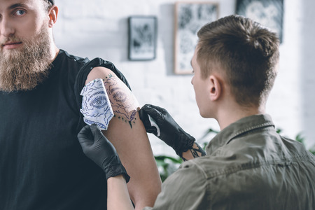 Tattoo artist in gloves working on shoulder piece sketch in studioの写真素材