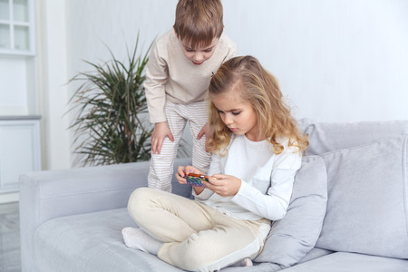 little kids using smartphone together on couch