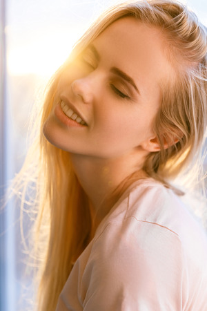 portrait of sensual young woman with closed eyes with sunset flare on backgroundの写真素材