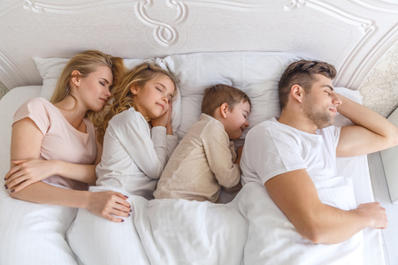 top view of young family sleeping together in bedの写真素材