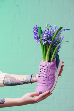 cropped image of girl holding shoe with hyacinth flowersの写真素材
