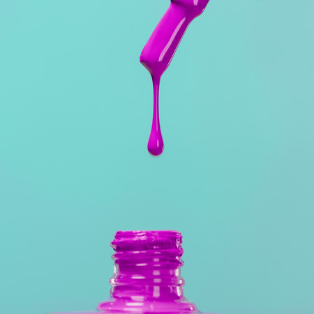 nail polish pouring down into bottle isolated on blueの写真素材