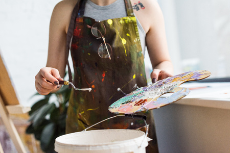 Close-up view of young inspired girl working with painting knife and palette in light studioの写真素材