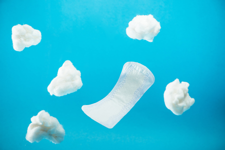 falling daily pad and pieces of cotton isolated on blueの写真素材