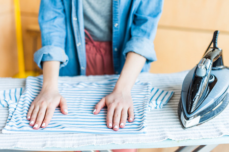 cropped shot of young woman ironing clothes at homeの写真素材