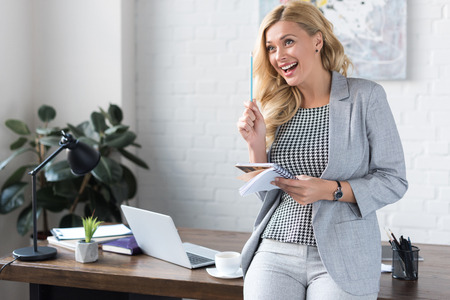 laughing businesswoman holding pencil and notebookの写真素材