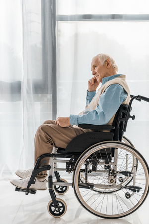 thoughtful sad senior man sitting in wheelchair in nursing homeの写真素材