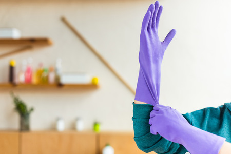 cropped shot of young woman wearing rubber gloves while cleaning houseの写真素材