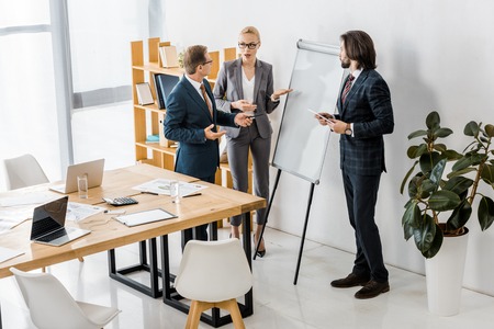office workers standing near white board and having discussion