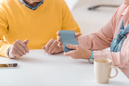 close up of senior people playing cards on white tableの写真素材