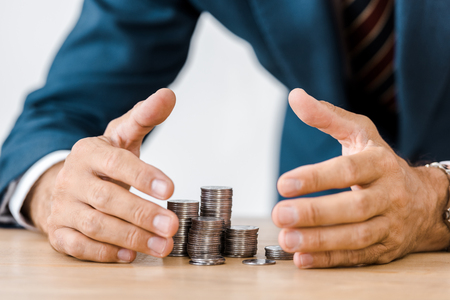 businessman grabbing silver coins at wooden tableの写真素材