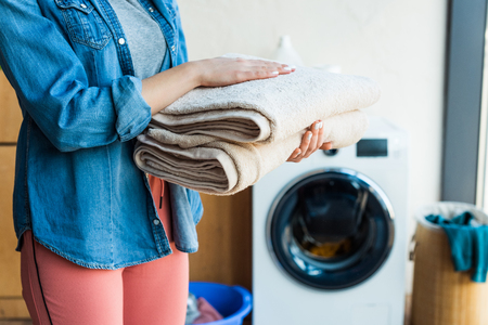 cropped shot of young woman holding stacked clean towels at homeの写真素材