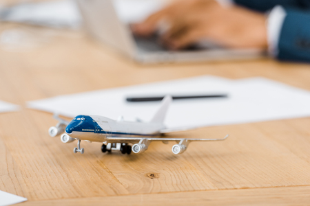 toy airplane at wooden table with office worker using laptop on blurred backgroundの写真素材