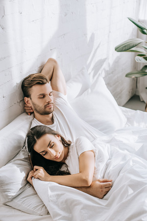 Beautiful young couple sleeping in bed in morningの写真素材