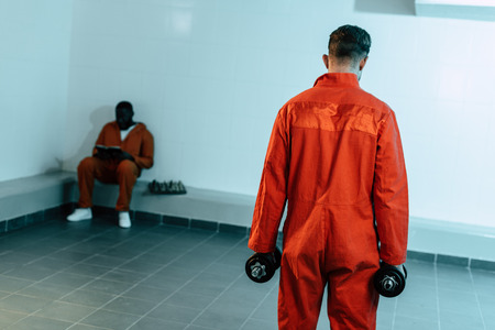 Rear view of prisoner training with dumbbells in prison cellの写真素材