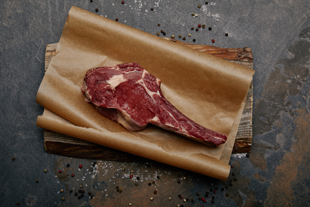 top view of raw rib eye steak on baking paper with spices on grey backgroundの写真素材