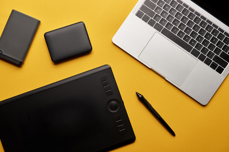 Top view of different graphic designer gadgets on yellow surfaceの写真素材
