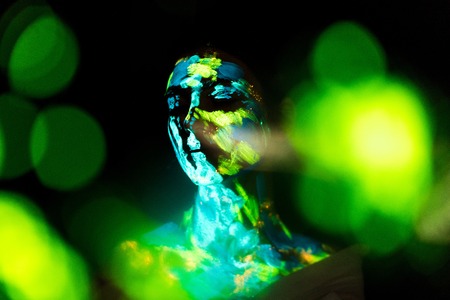 Model with colorful neon paints on body posing on black backdropの写真素材