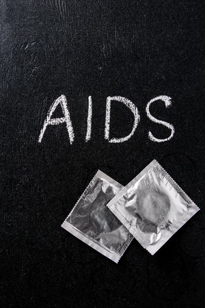 Top view of aids sign and silver condoms on black backgroundの写真素材