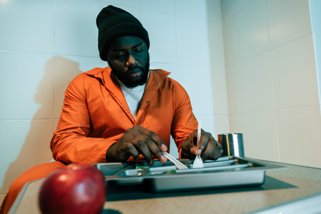 African american inmate eating in prison cellの写真素材