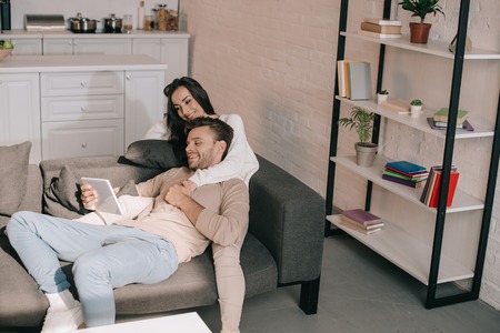 high angle view of beautiful young couple using tablet together on sofa at homeの写真素材