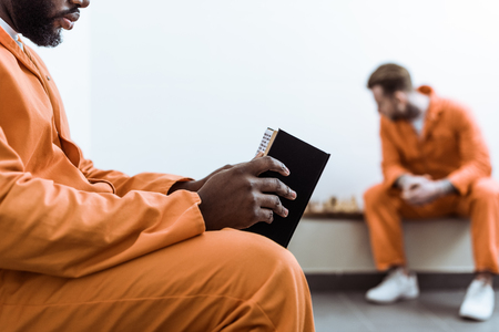 Cropped image of African american prisoner reading book