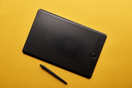 Top view of graphics tablet and pen on yellow surfaceの写真素材