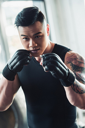 Young Asian sportsman wearing black boxing glovesの写真素材