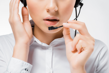 Close up of young call center operator touching headset and speaking in microphoneの写真素材