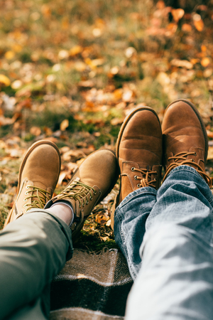 Camera point of view on two pairs of orange boots in beautiful foliage in autumnの写真素材