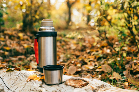 metallic camping thermos on beautiful autumnal backgroundの写真素材