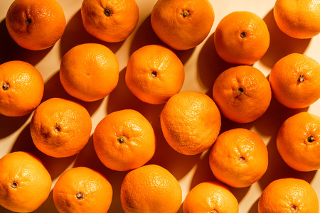 Full frame of arranged fresh wholesome tangerines on beige background