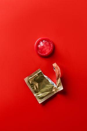 top view of red condom and golden packaging on red backgroundの写真素材