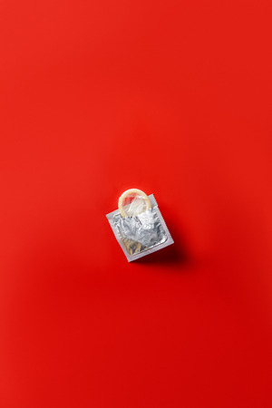 top view of condom in silver packaging on red backgroundの写真素材