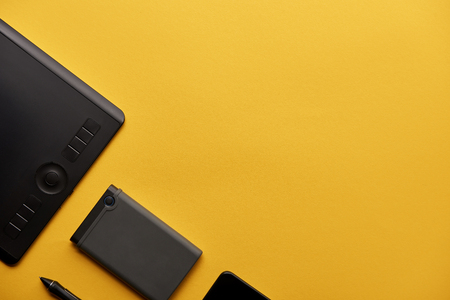 top view of graphics tablet and portable hdd on yellow surfaceの写真素材