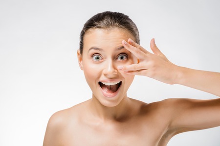 young beautiful woman with face expression and fingers near faceの写真素材