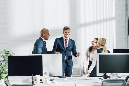 smiling young multiethnic business people talking in open space officeの写真素材