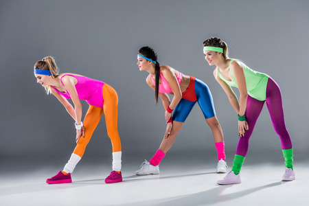 beautiful sporty girls in 80s style sportswear exercising together on greyの写真素材